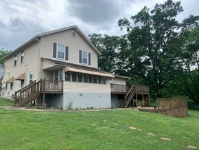 Lindale house for rent - A house with a grey and beige exterior has a deck and a small tree in front.