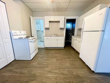 Louisville house for rent - A kitchen with white appliances and wooden floors.