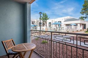 Phoenix apartment for rent - A balcony with a wooden chair and table overlooking a pool area.