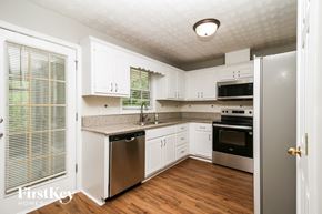 Covington house for rent - A kitchen with white cabinets and a wooden floor.