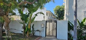 Cudahy apartment for rent - A white house with a black gate and a tree in front.