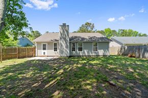Midway Park house for rent - A house with a white door and a chimney is surrounded by a fence and trees.