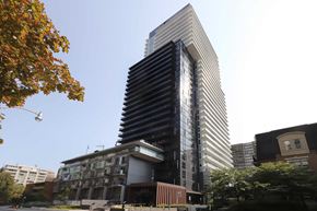 Toronto apartment for rent - A tall building with a black and white striped facade stands in front of a tree with orange leaves.