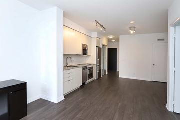 Toronto apartment for rent - A kitchen with white cabinets and a black trash can.