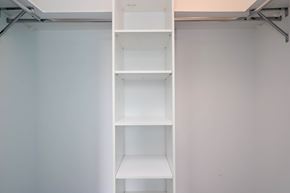 Toronto apartment for rent - A white shelving unit with four shelves is mounted on a white wall.