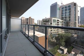 Toronto apartment for rent - A balcony with a glass railing overlooks a cityscape.