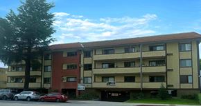 Van Nuys apartment for rent - A multi-story apartment building with cars parked in front.