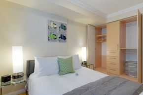 Toronto apartment for rent - A bedroom with a bed, nightstand, and a wall art of tractors.