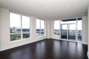 Toronto apartment for rent - A large empty room with wooden floors and a view of the city through the windows.