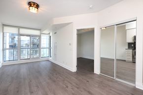 Toronto apartment for rent - A spacious room with a large window and wooden flooring.