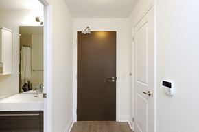 Toronto apartment for rent - A white bathroom with a brown door and a white sink.