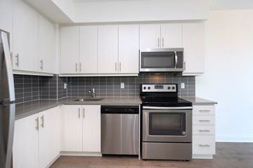 Toronto apartment for rent - A modern kitchen with white cabinets and stainless steel appliances.