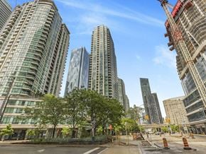 Toronto apartment for rent - A city street with a construction site in the foreground and tall buildings in the background.