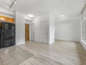 Toronto apartment for rent - A spacious room with wooden flooring and white walls.