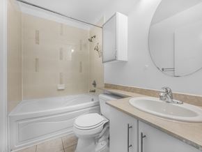 Toronto apartment for rent - A white toilet sits next to a white bathtub in a bathroom.