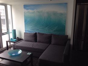 Toronto apartment for rent - A living room with a grey couch and a large painting of a wave on the wall.