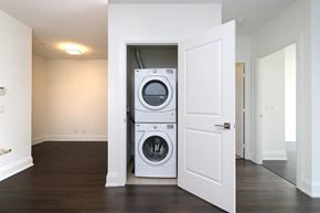 Toronto apartment for rent - A white door is open to reveal a stacked washer and dryer in a clean, empty room.