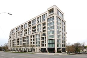 Toronto apartment for rent - A large, modern building with many windows is situated on a street corner.