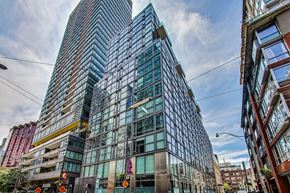 Toronto apartment for rent - A modern glass building stands tall in an urban setting.