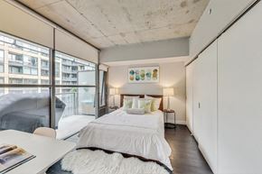 Toronto apartment for rent - A bedroom with a large bed and a view of a building outside the window.