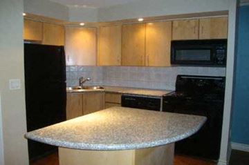 Toronto apartment for rent - A kitchen with a black refrigerator, black oven, and a granite counter.