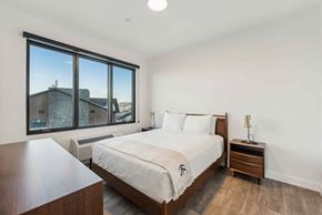 Park City apartment for rent - A bedroom with a large bed and a wooden nightstand.