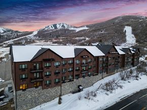 Park City apartment for rent - A large building with a lot of windows is surrounded by snow.