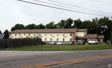 Indianapolis apartment for rent - A large white building with a brown roof is surrounded by a wooden fence.