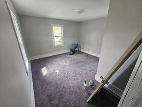 Lima house for rent - A man is kneeling on a carpeted floor in a room with a window.
