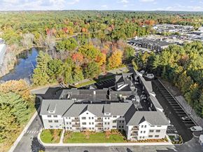 Bedford apartment for rent - A large white building with a parking lot in front of it.