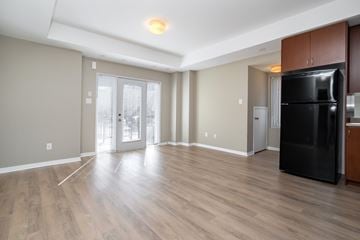 Mississauga apartment for rent - A black refrigerator is in a kitchen with wood floors and white walls.