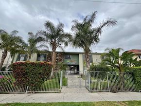 North Hollywood apartment for rent - A building with a green awning is surrounded by a metal fence and palm trees.