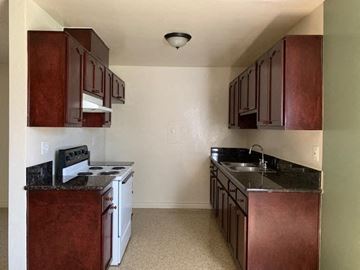 North Hollywood apartment for rent - A kitchen with brown cabinets and a black stove top oven.