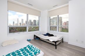 Mississauga apartment for rent - A bedroom with a large bed and a view of the city skyline.