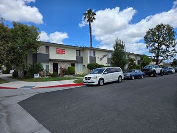 Downey apartment for rent - A white van is parked in front of a building with a red sign.