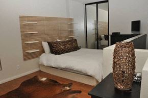 Los Angeles apartment for rent - A bedroom with a bed, a cowhide rug, and a tall vase on a table.