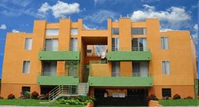 Los Angeles apartment for rent - A large orange and green apartment building with a blue sky in the background.