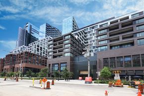 Toronto apartment for rent - A city street with orange traffic cones and buildings in the background.