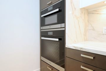 Toronto apartment for rent - A modern kitchen with a stainless steel oven and a marble backsplash.