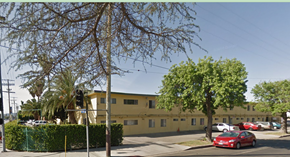 Van Nuys apartment for rent - A street view of a yellow building with a red car parked in front.