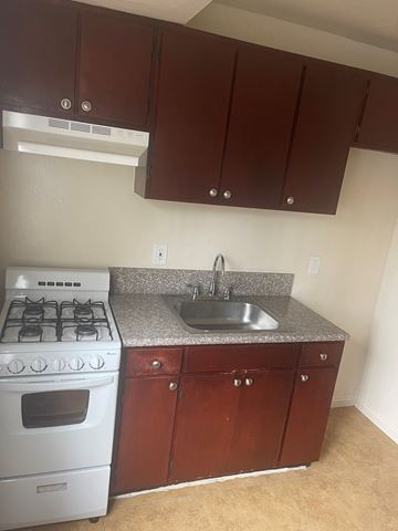 Van Nuys apartment for rent - A kitchen with a white stove and brown cabinets.