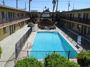 Van Nuys apartment for rent - A pool surrounded by a black fence and bushes.