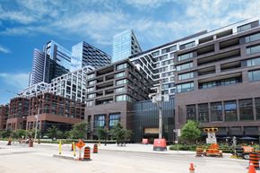 Toronto apartment for rent - A city street with orange cones and buildings in the background.