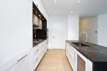 Toronto apartment for rent - A modern kitchen with white cabinets and a black countertop.