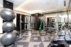 Toronto apartment for rent - A gym with a variety of equipment including dumbbells, a treadmill, and a weight machine.