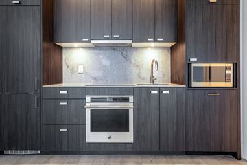 Toronto apartment for rent - A modern kitchen with dark wood cabinets and a marble backsplash.