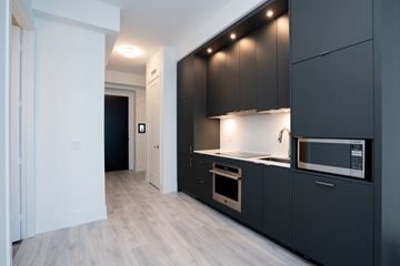 Toronto apartment for rent - A modern kitchen with dark grey cabinets and a white countertop.