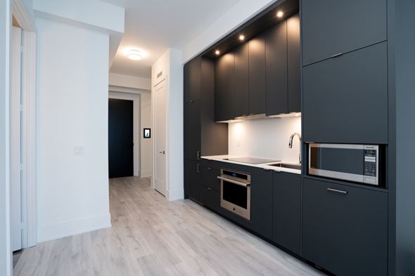 Toronto apartment for rent - A modern kitchen with dark grey cabinets and a white countertop.