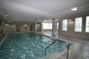 Mississauga apartment for rent - A large indoor swimming pool with a metal ladder on the side.