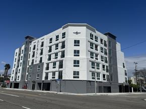 Inglewood apartment for rent - A large white building with a black emblem on the top left corner.